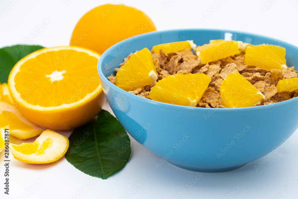 Cereal flake with pieces orange fruits slice in the blue bowl isolated on white background Cereal flake with pieces orange fruits slice in the blue bowl isolated on white background