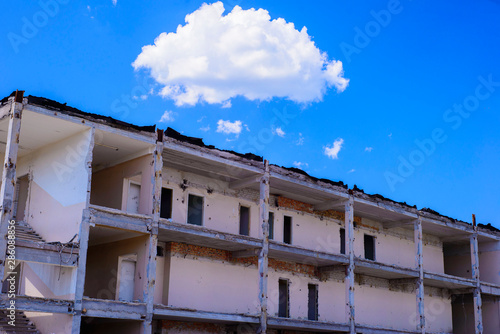 Old destroyed building against blue sky and big cloud. Ruin. Concept of destruction © Алексей Доненко