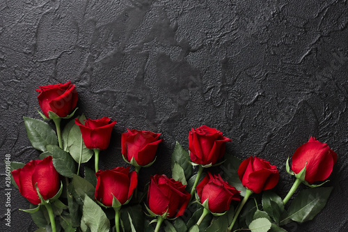 Red roses on a black, textured, stone background. Place for text, top view