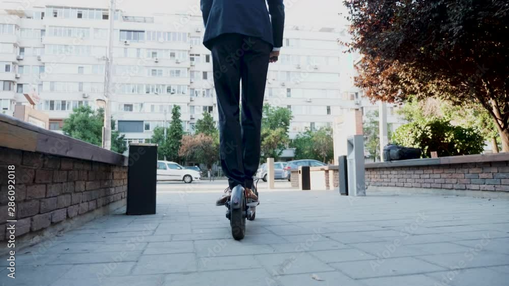 Businessman using an electric scooter to get to work. Eco friendly transport Businessman using an electric scooter to get to work. Eco friendly transport