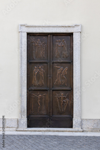 metal church door with high relief religious symbols, italy