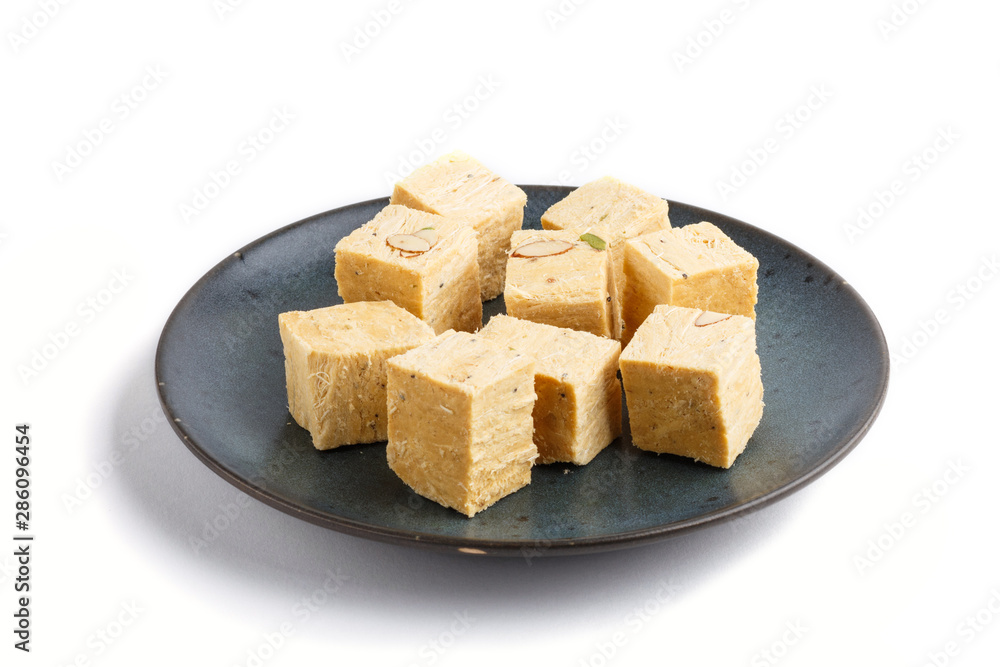 traditional indian candy soan papdi in blue ceramic plate isolated on a white background. side view traditional indian candy soan papdi in blue ceramic plate isolated on a white background. side view