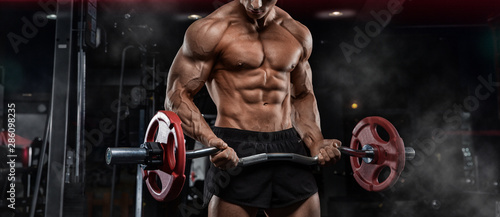 Billede på lærred oung adult bodybuilder doing weight lifting in gym.