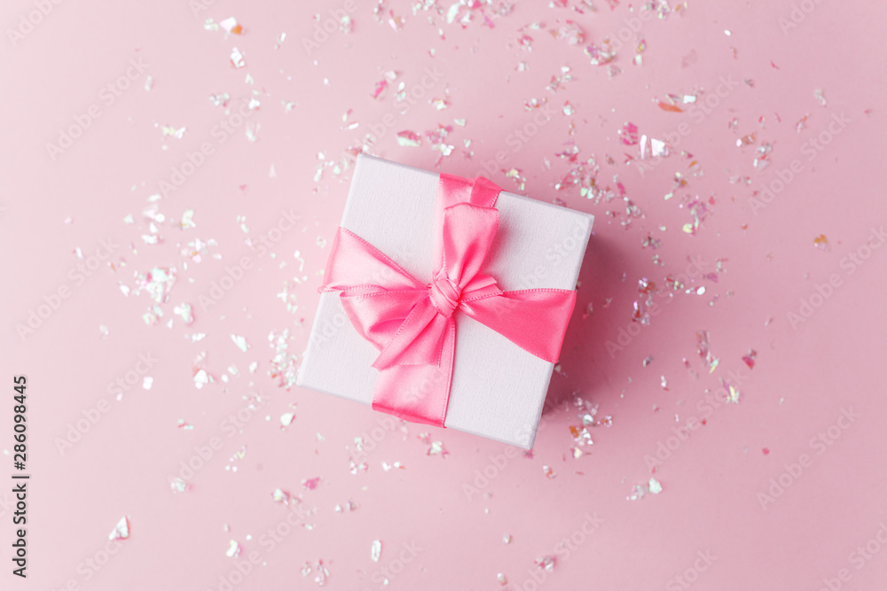 White gift box and confetti on pink background with copy space for text. fashion and shopping concept. wedding, marriage or birthday composition. flat lay, top view White gift box and confetti on pink background with copy space for text. fashion and shopping concept. wedding, marriage or birthday composition. flat lay, top view