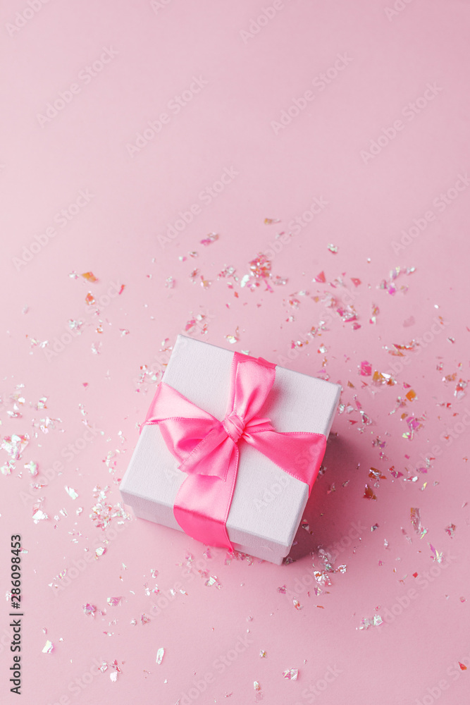 White gift box and confetti on pink background with copy space for text. fashion and shopping concept. wedding, marriage or birthday composition. flat lay, top view