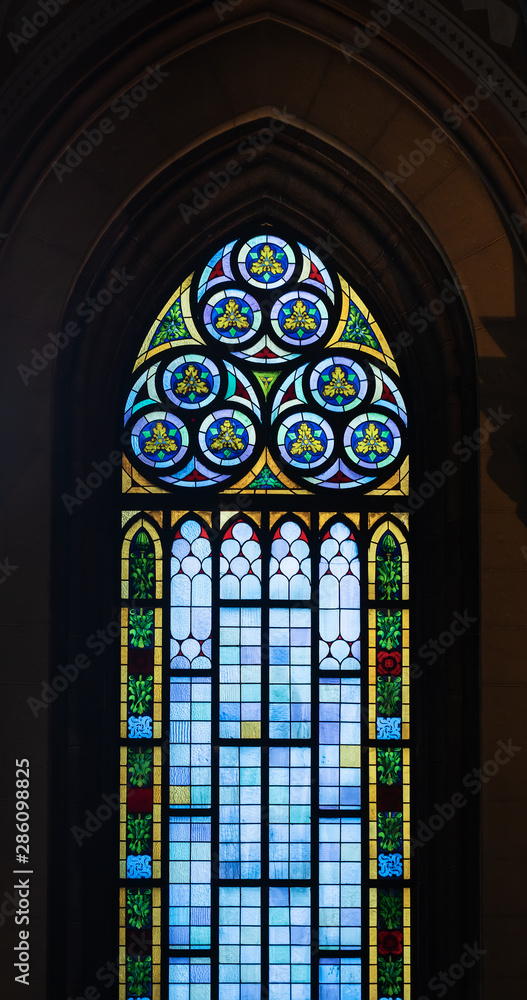 A high stained glass window with colored accents in an old Catholic church. A high stained glass window with colored accents in an old Catholic church.