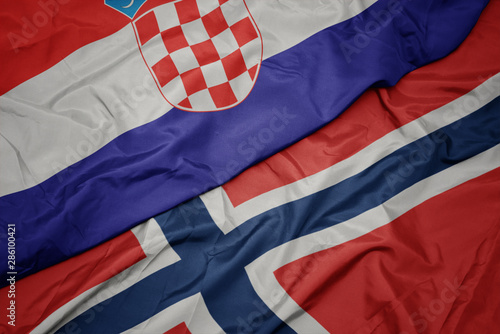waving colorful flag of norway and national flag of croatia.