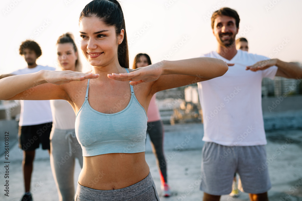 Group of athletic young people, friends in sportswear doing exercises. Sport outdoors