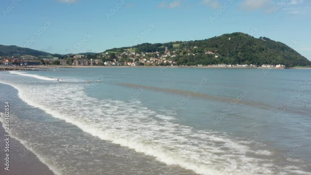 British beach summer holiday aerial shot over waves with family swimming in sea British beach summer holiday aerial shot over waves with family swimming in sea