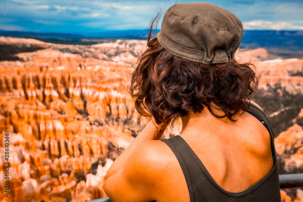 A young woman looking at the canyon from Bryce Point in Bryce National Park. Utah, United States