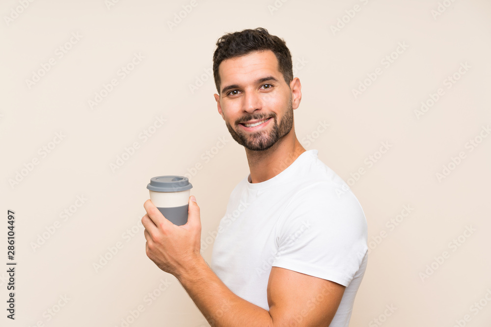 Handsome man over isolated background holding a take away coffee Handsome man over isolated background holding a take away coffee