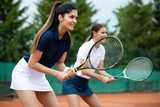 Young happy fit women playing tennis on tennis court