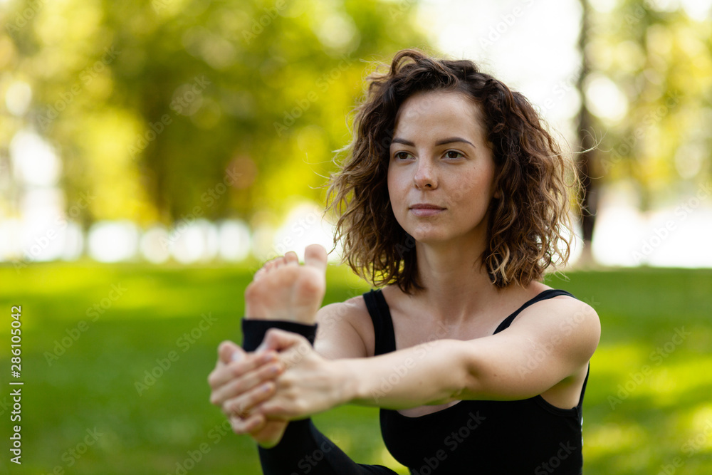Young woman in park practicing yoga. Standing Hand to Toe (Preparation). Young woman in park practicing yoga. Standing Hand to Toe (Preparation).