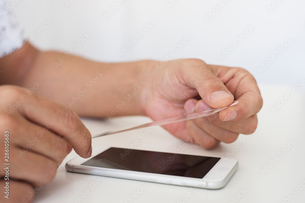 man installing a screen protector in a smartphone man installing a screen protector in a smartphone