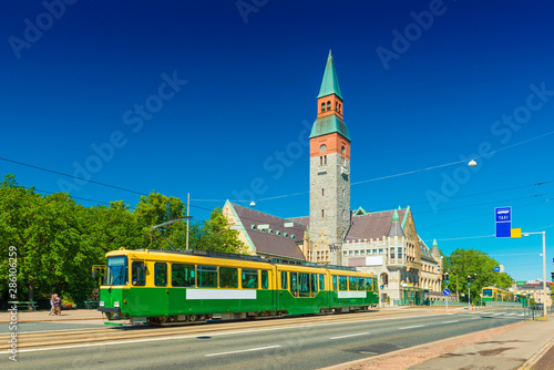 Obraz na płótnie View of a city tram in Helsinki and the old historical building of The National Museum of Finland with clear blue sky in the background w salonie