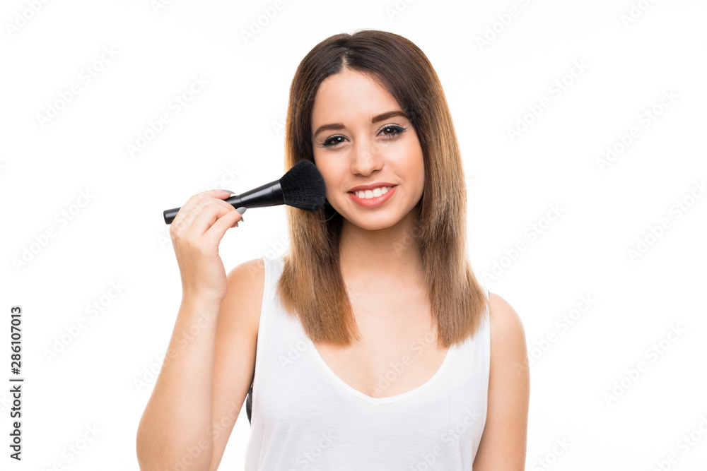 Young woman over isolated white background with makeup brush Young woman over isolated white background with makeup brush