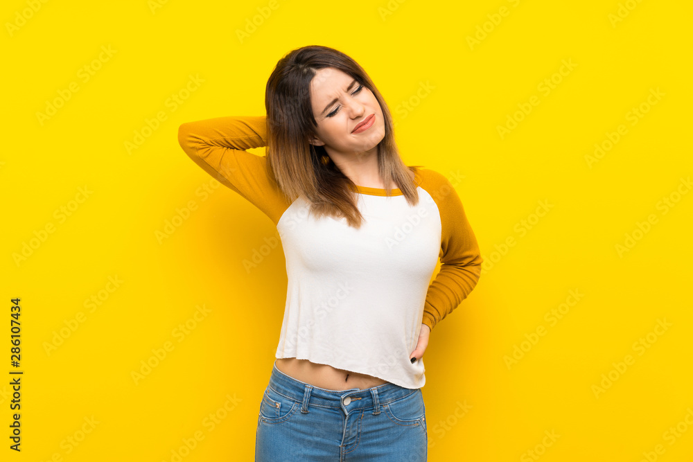Pretty young woman over isolated yellow wall with neckache Pretty young woman over isolated yellow wall with neckache