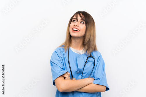 Young nurse woman over white wall looking up while smiling © luismolinero