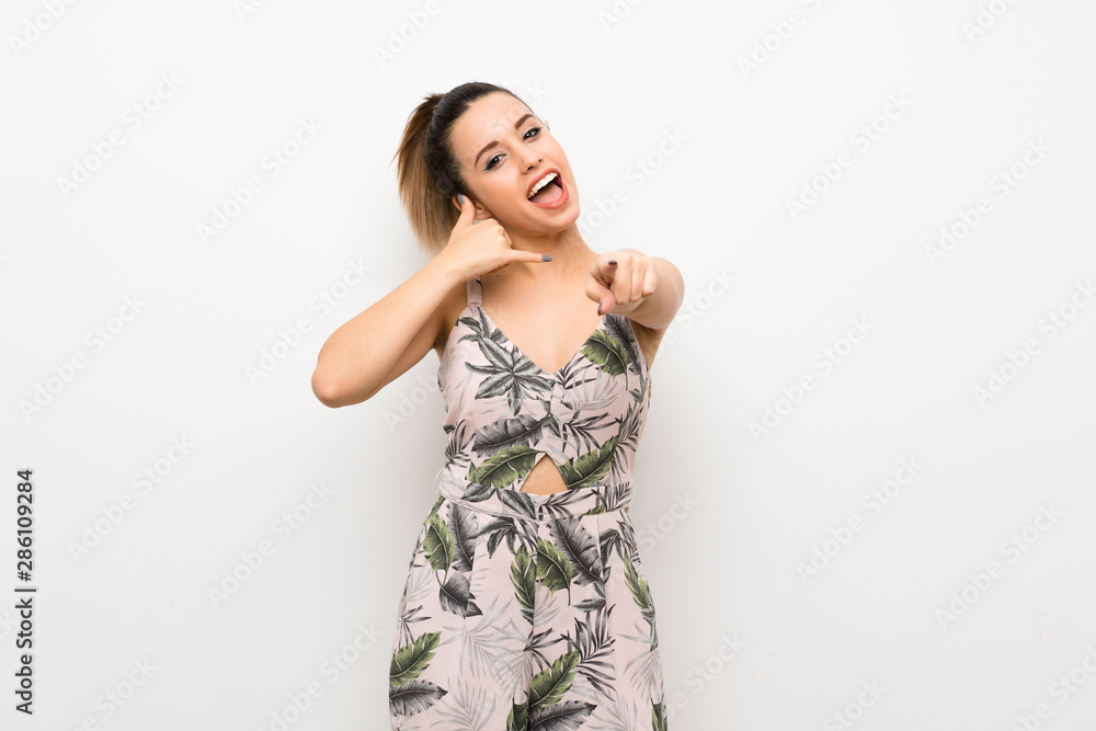 Young woman over isolated white background making phone gesture and pointing front