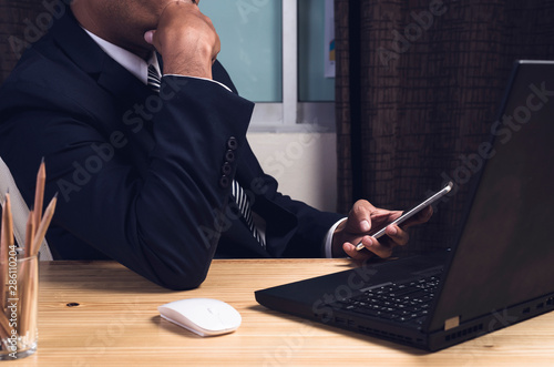 Asian businessman Searching for information in smartphone. at work table,office desk background,technology for business concept.