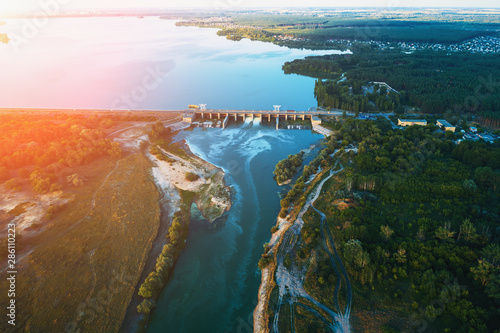 Aerial view of Dam at reservoir with flowing water at sunset, hydroelectricity power station, drone photo