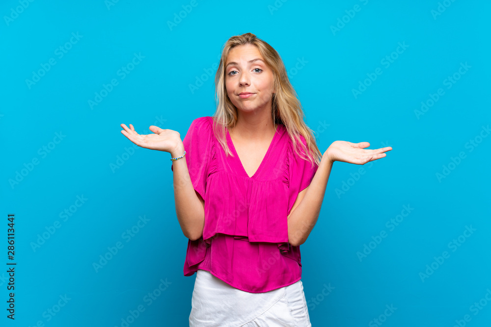 Blonde young woman over isolated blue background having doubts while raising hands Blonde young woman over isolated blue background having doubts while raising hands