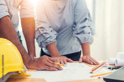 Asian engineer meeting for architectural project and pointing at a drawings on table in office.Construction design concept.vintage color tone.