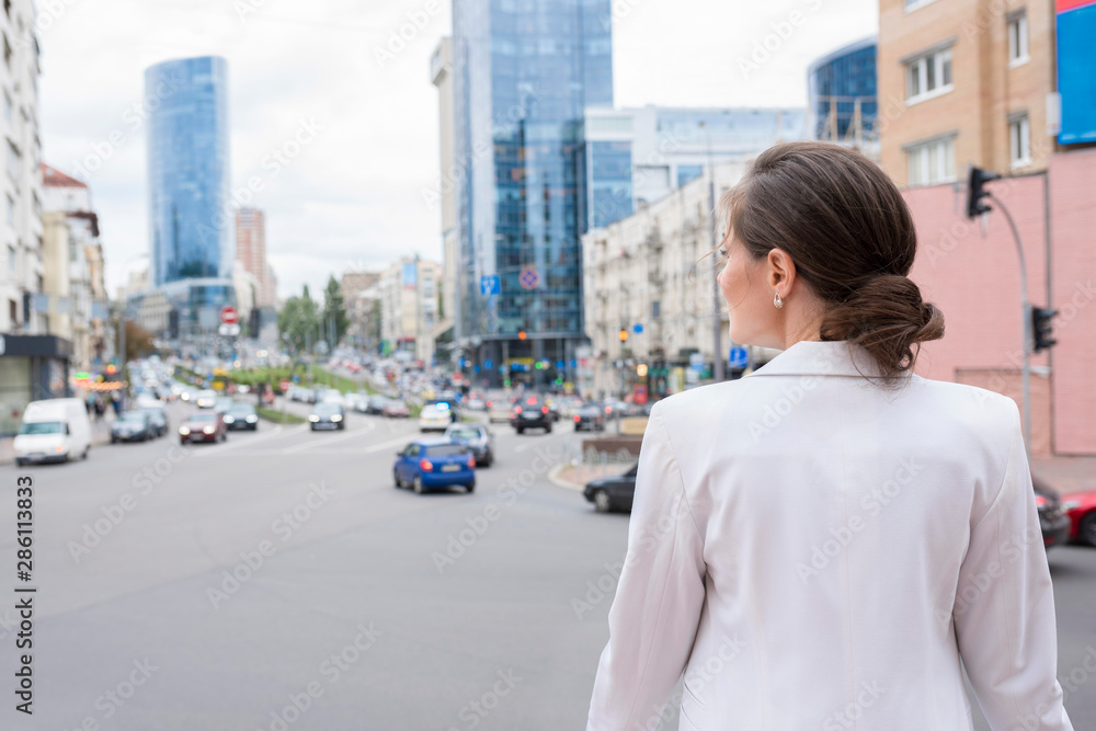 A young woman at the city street background, a back view.