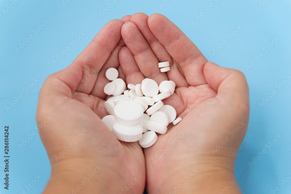 Pills in hand on a blue background. Alternative homeopathy is a medicinal plant.The concept of health and medicine. Flatley. The view from the top. copyspace for text. Pills in hand on a blue background. Alternative homeopathy is a medicinal plant.The concept of health and medicine. Flatley. The view from the top. copyspace for text.