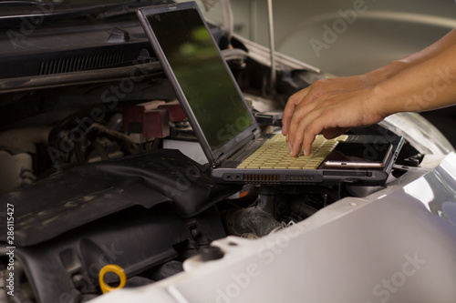 Machanic Man analyze car engine while service a Maintenance at repair shop.