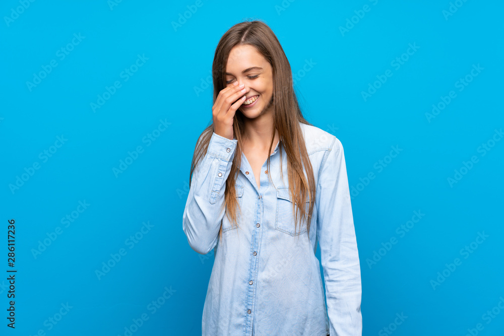 Young woman over isolated blue background smiling a lot Young woman over isolated blue background smiling a lot