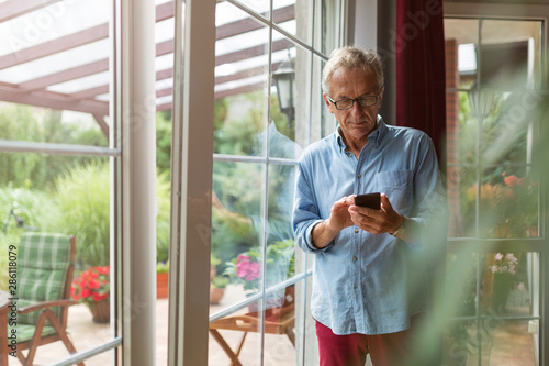 Senior man using mobile phone at home