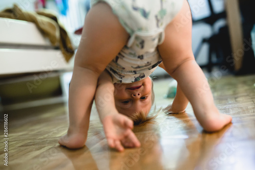 cute little child standing upside down at home photo