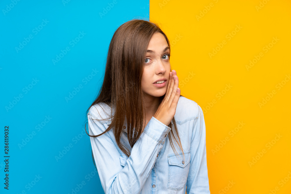 Young woman over colorful background whispering something Young woman over colorful background whispering something