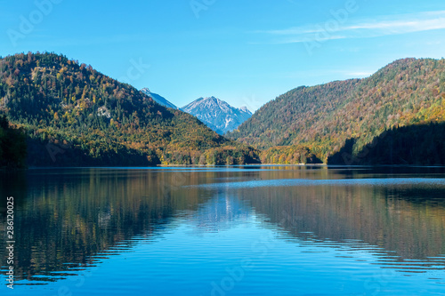 Symmetric reflection of Alps and the forest on shores in the water surface in the lake in autumn
