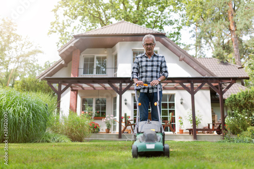 Elderly man mowing the lawn photo