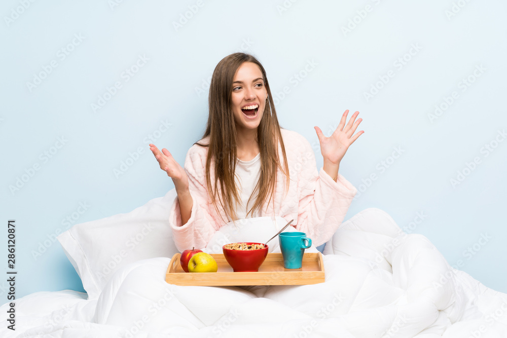 Young woman in dressing gown with breakfast with surprise facial expression Young woman in dressing gown with breakfast with surprise facial expression