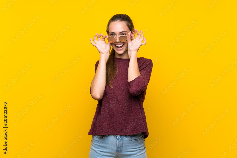 Young woman over isolated yellow background with glasses and smiling Young woman over isolated yellow background with glasses and smiling