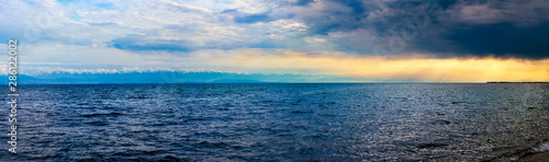 Beautiful panoramic sea view at sunset, lit by evening sunlight in cloudy weather © Юрий Кузнецов