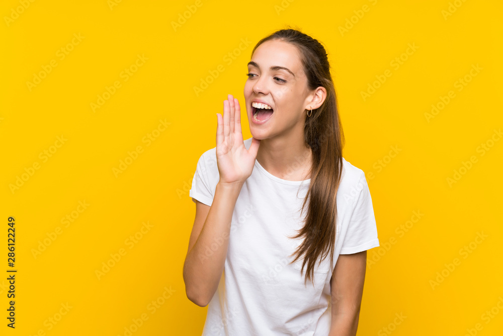 Young woman over isolated yellow background shouting with mouth wide open Young woman over isolated yellow background shouting with mouth wide open