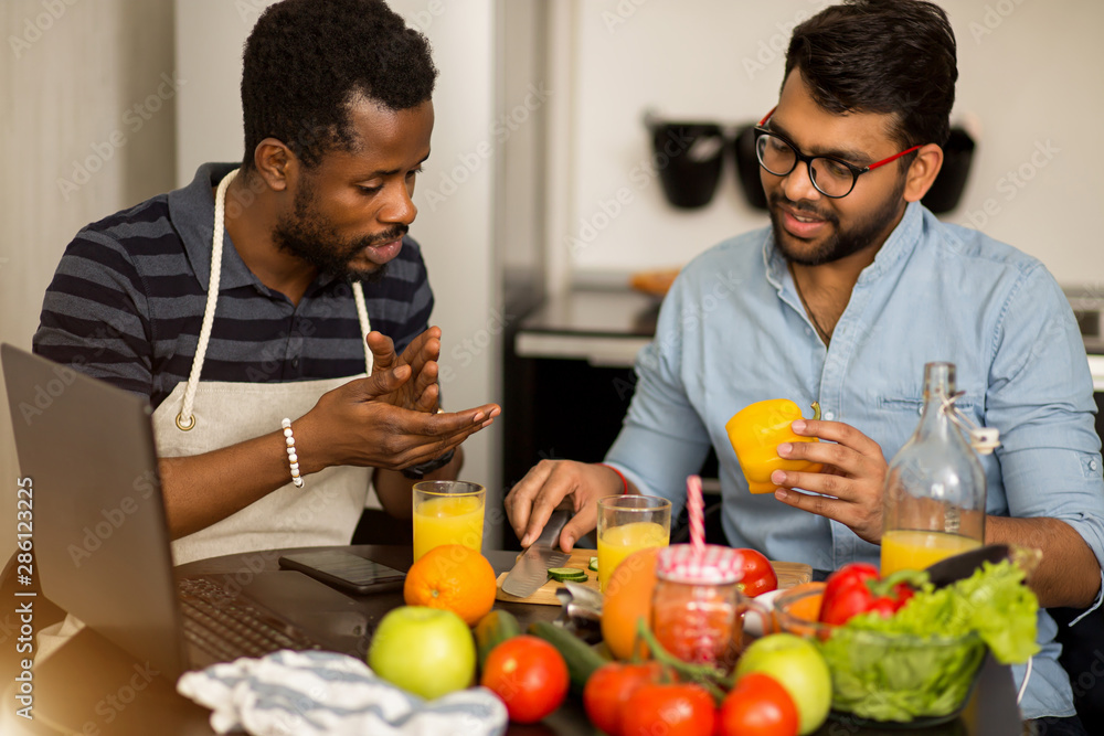 Two men using laptop in kitchen Two men using laptop in kitchen