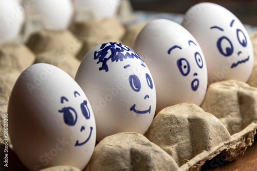 Lovely eggs in cardboard box. Eggs with emotions. White eggs in cardboard box with different faces painted on them. Boys and girl