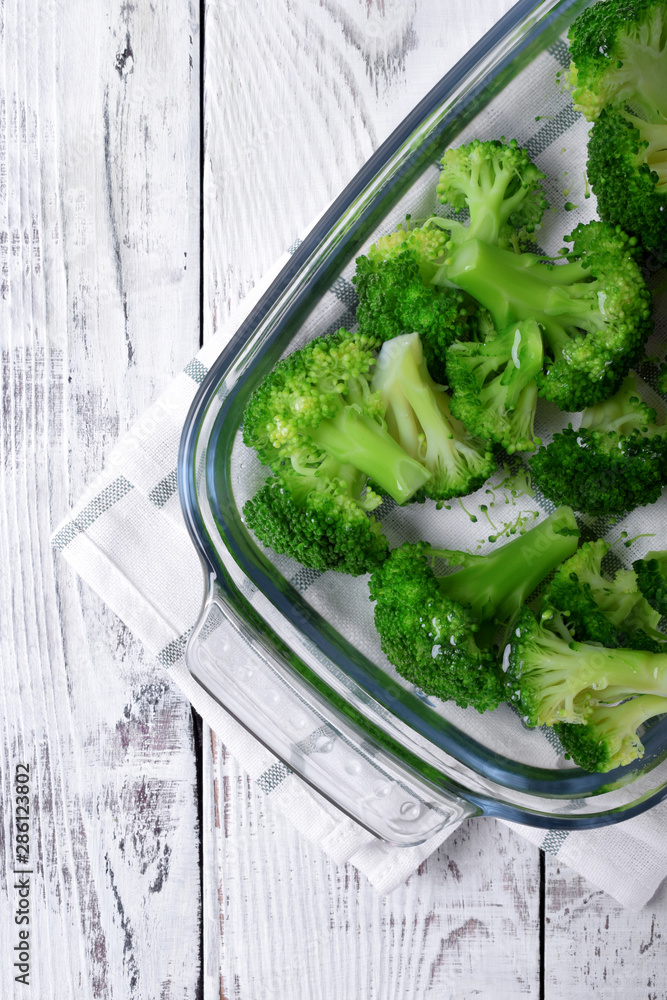 Blanched broccoli cabbage cooling down in cold water in a glass dish on white table Blanched broccoli cabbage cooling down in cold water in a glass dish on white table