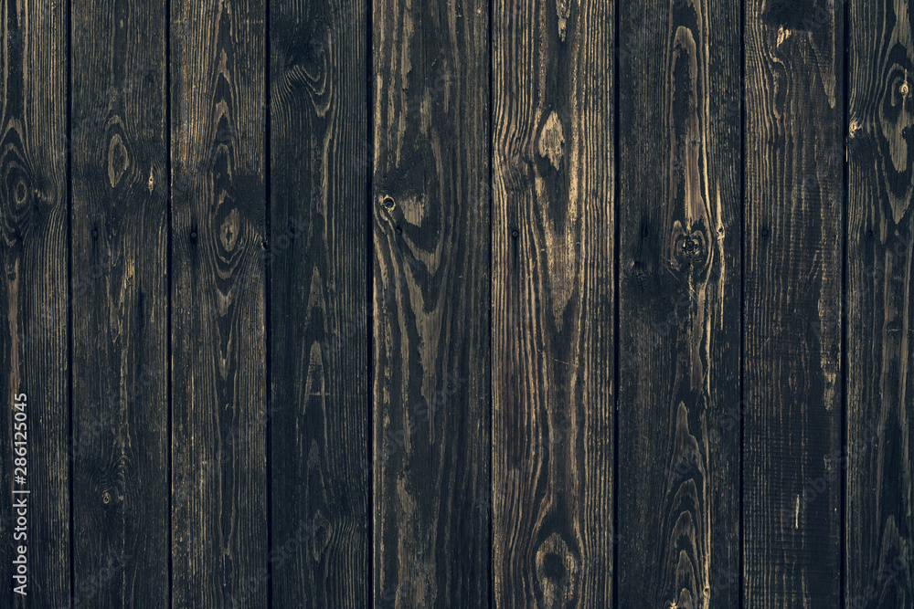 Dark shabby wooden fence with nails. Texture of black planks. Old wood brown boards. Vintage timber background. Natural pattern of hurdwood.