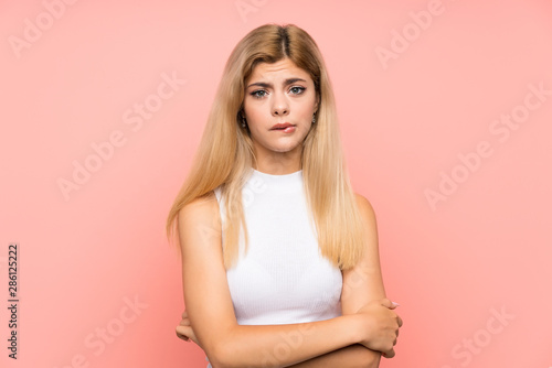 Teenager girl over isolated pink background sad