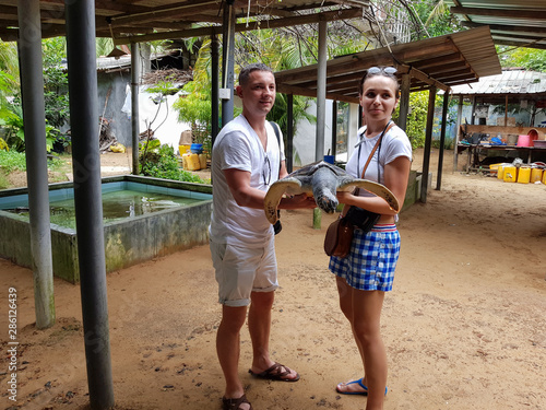Young couple holding a big turtle in their hands. Turtle Rescue Center. Turtle farm in Sri Lanka