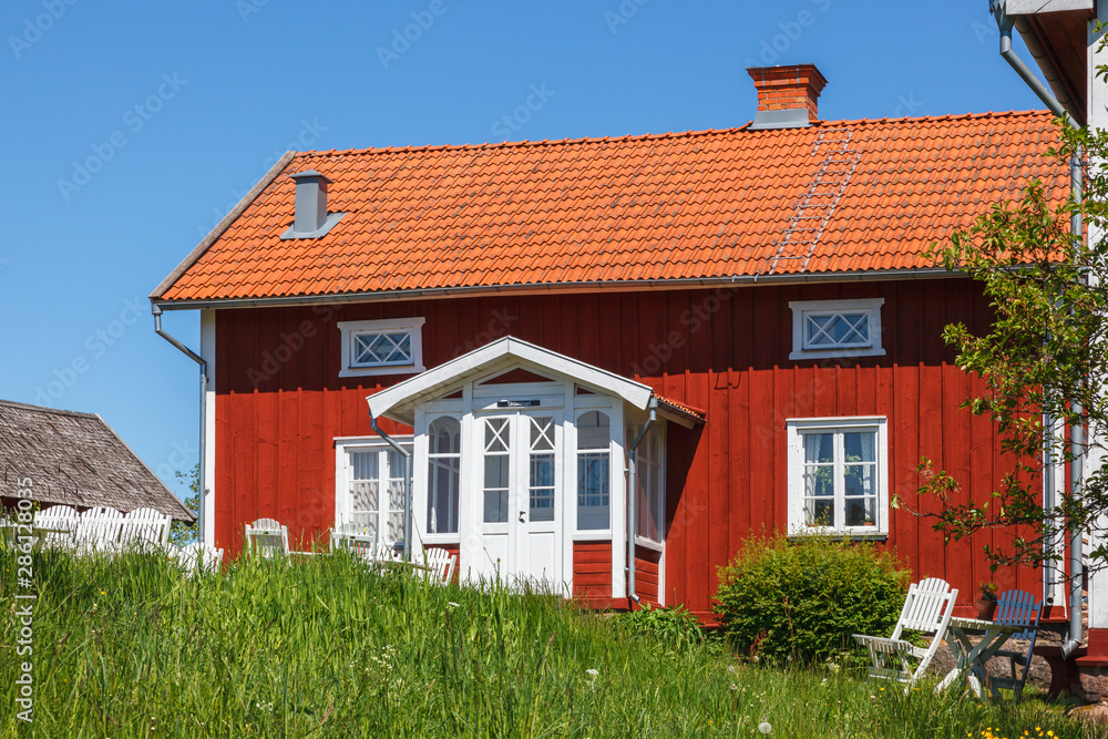 Red old cottage with garden furniture in the summer