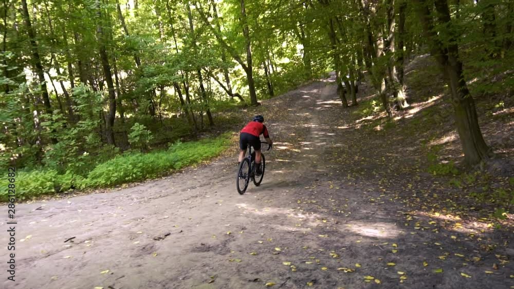 Young man biking on a forest road in a sammer day. active recreation, sport, healthy lifestyle. slow motion Young man biking on a forest road in a sammer day. active recreation, sport, healthy lifestyle. slow motion