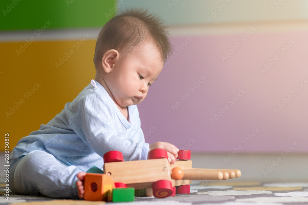 Asian male toddler playing with his toy on the floor. Trying to solve problem. With light leak effect. Asian male toddler playing with his toy on the floor. Trying to solve problem. With light leak effect.
