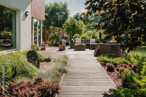 Bild auf Leinwand Wooden path to terrace in the garden with trendy garden furniture